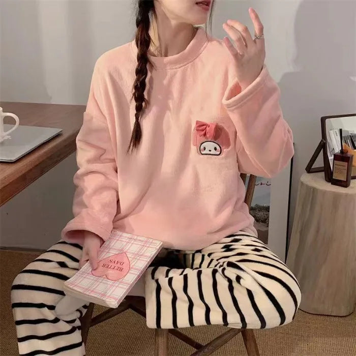 Person wearing a pink sweatshirt with a cartoon character and striped pants, sitting on a chair.