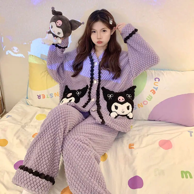 Person wearing a purple pajama set with cat designs on a bed.