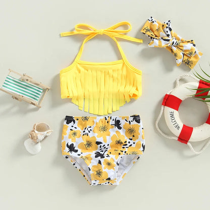 Yellow bikini set with floral pattern, headband, and beach accessories on a light background