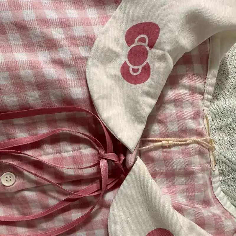 Pink checkered fabric with a white bow and pink ribbon on a textured surface
