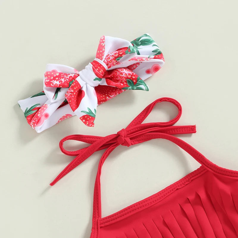 Red bikini top with strawberry print headband on a beige background