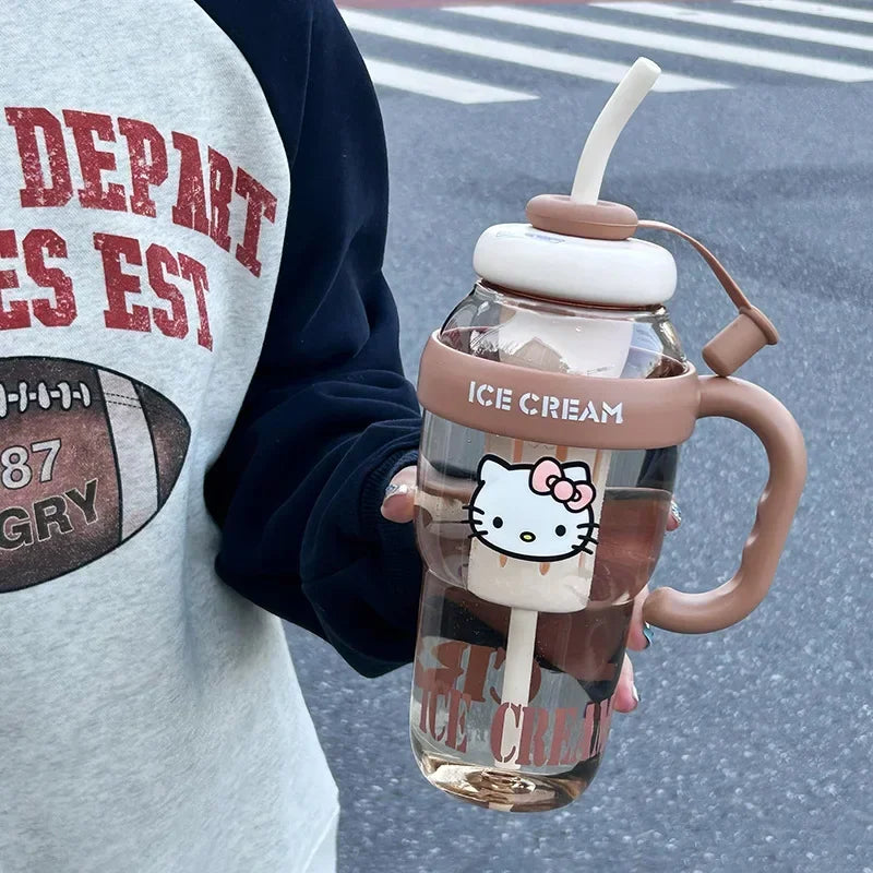 Glass cup with handle and straw, resembling ice cream, held by a person wearing a sports jersey.