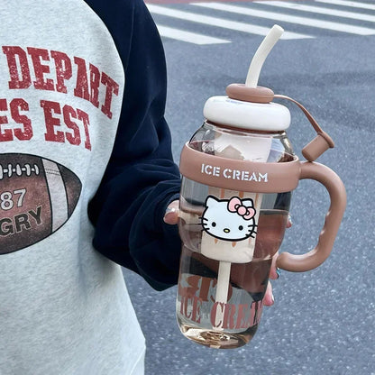 Glass cup with handle and straw, resembling ice cream, held by a person wearing a sports jersey.