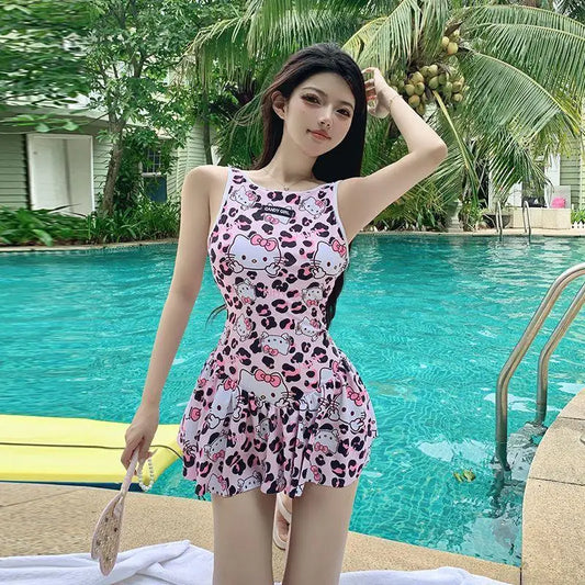 Woman in a pink patterned swimsuit standing by a pool with palm trees in the background