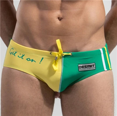 Green and yellow swim briefs with text and branding on a plain background