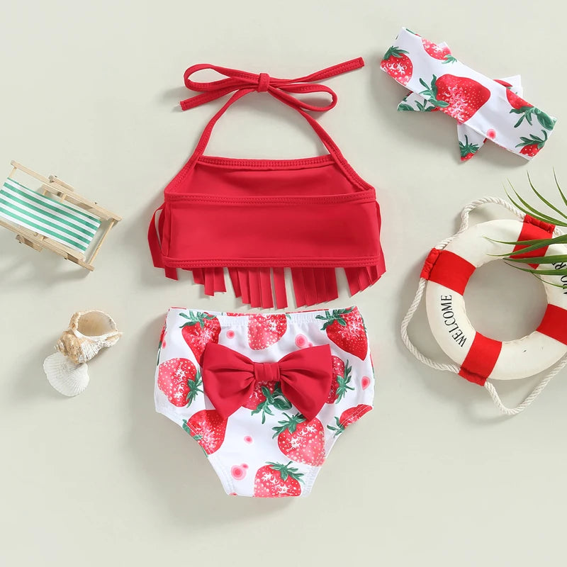 Red bikini set with strawberry pattern and accessories on a light background