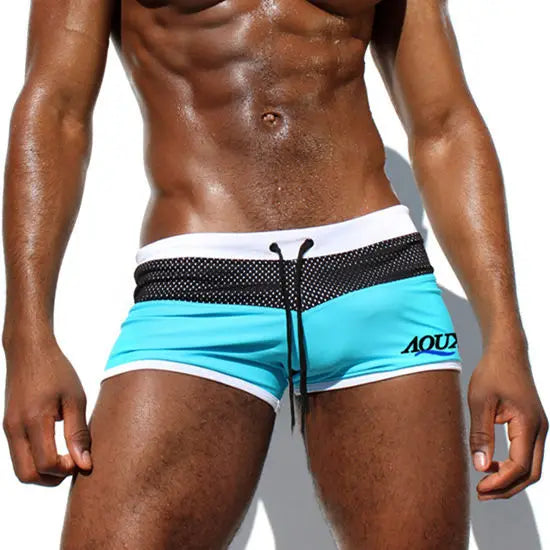 Man wearing turquoise swim shorts with black and white accents on a white background