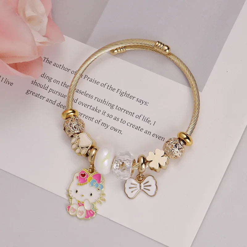 Gold bracelet with charms including a Hello Kitty figure on a book page background