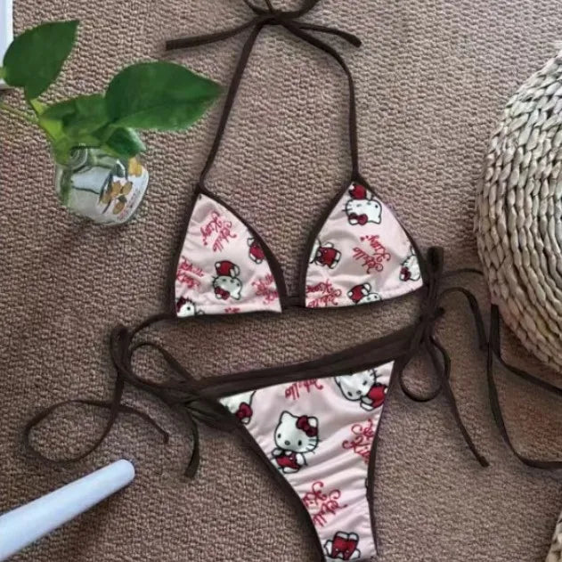 Hello Kitty bikini set on a textured surface with a plant and straw hat in the background