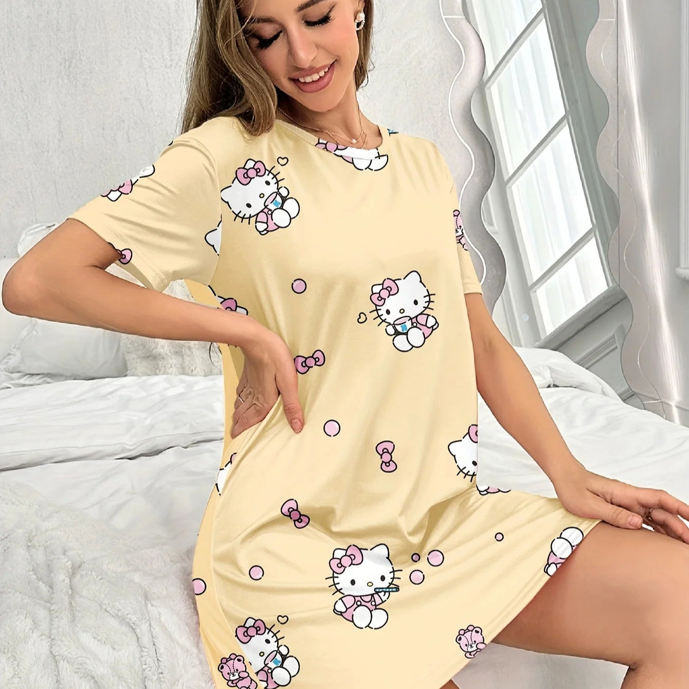 Woman wearing a yellow nightshirt with Hello Kitty patterns in a bedroom setting.