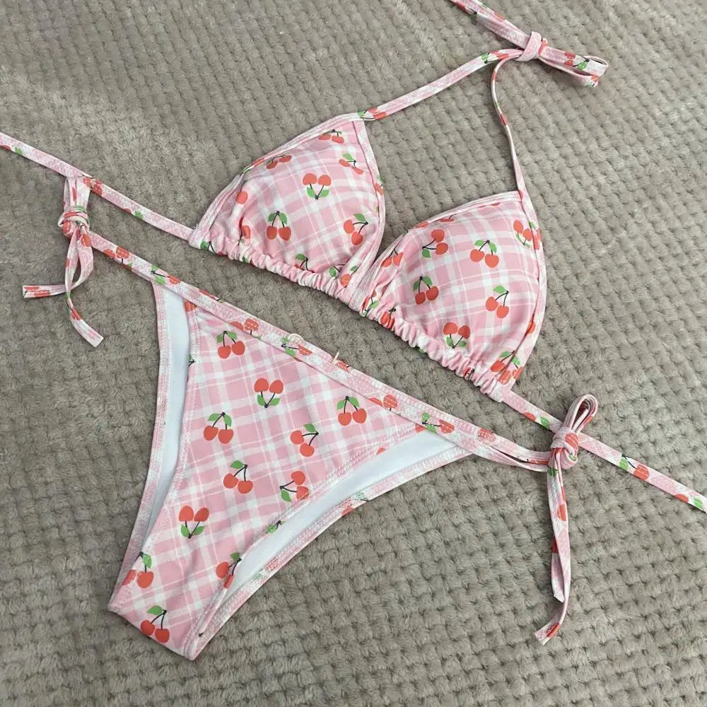 Pink bikini set with cherry pattern on a textured surface