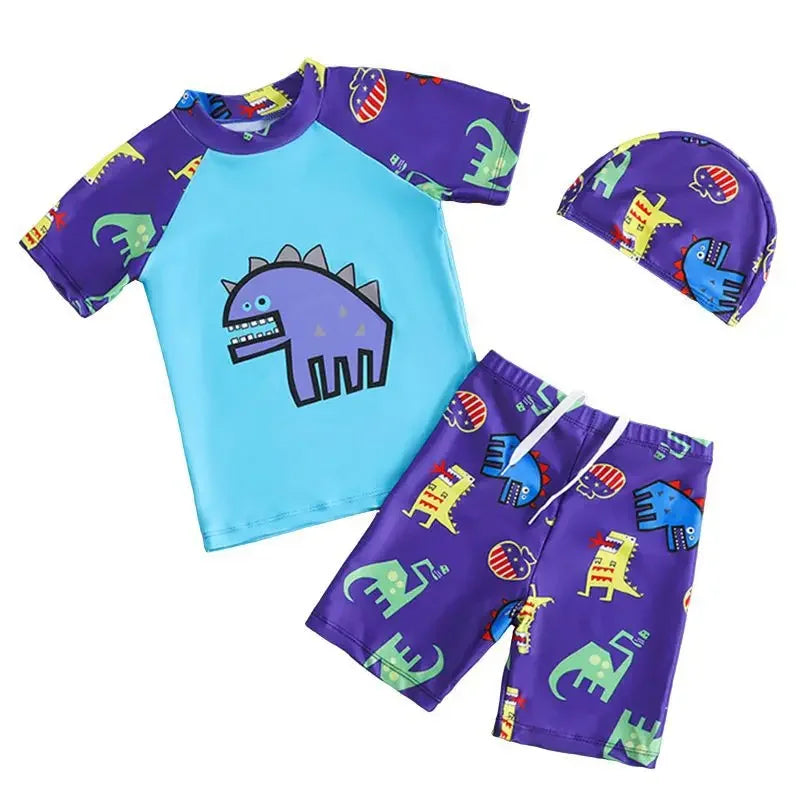 Children's swim set with blue shirt, purple shorts, and hat featuring dinosaur patterns on a white background.