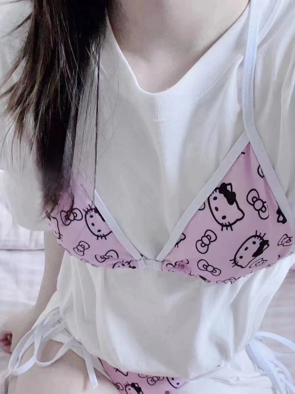Person wearing a white top with a pink Hello Kitty patterned bra.