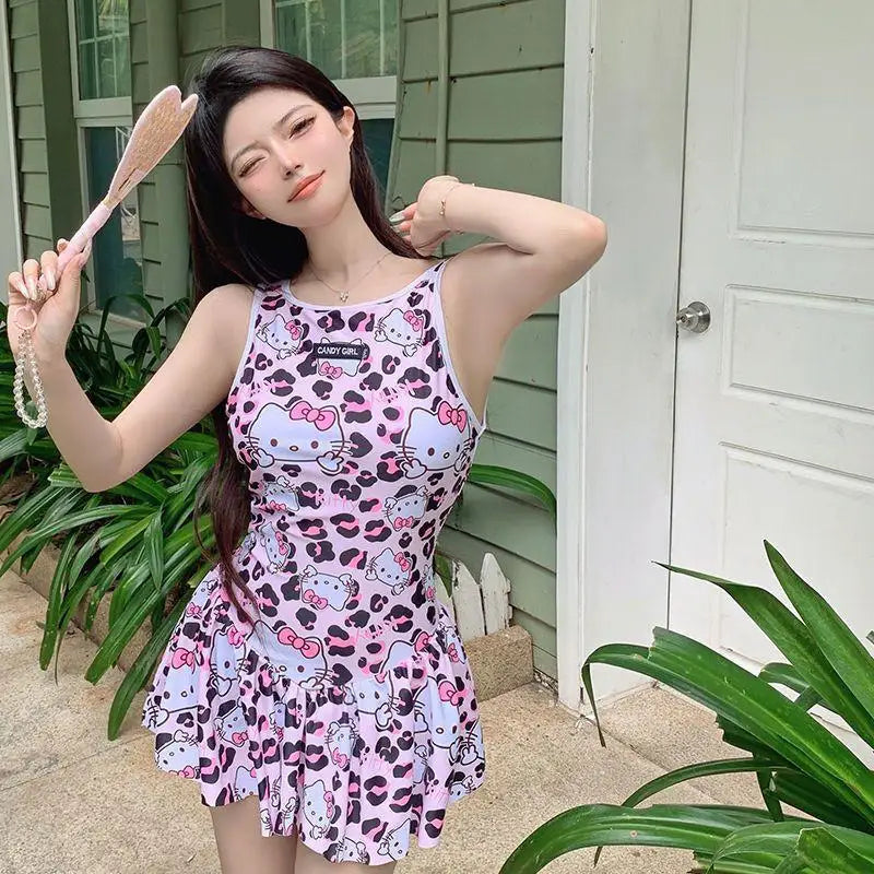 Woman wearing a Hello Kitty dress with a pink and white pattern, holding a bunny ears headband.