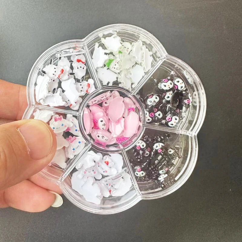 Clear plastic container with compartments filled with small decorative items, held by a hand against a dark background.
