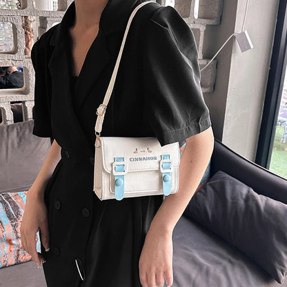 Person holding a white handbag with blue accents indoors