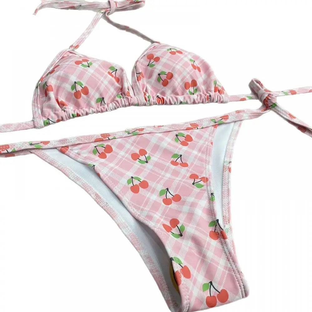 Pink bikini set with cherry pattern on a white background
