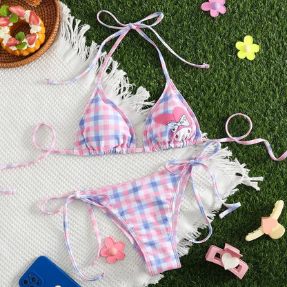 Pink and blue checkered bikini set on a white blanket with grass in the background