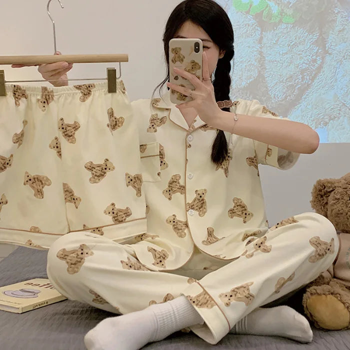 Person wearing a cream-colored pajama set with bear pattern, sitting on a bed.