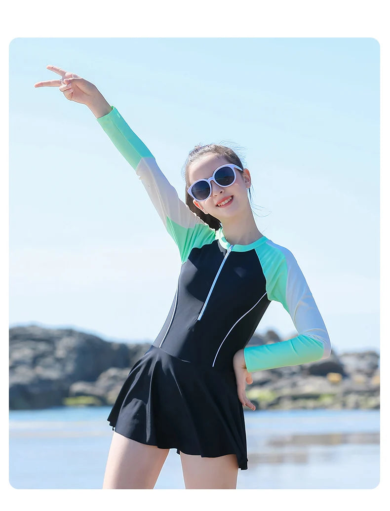 Woman in a black and green swimsuit with sunglasses on a beach