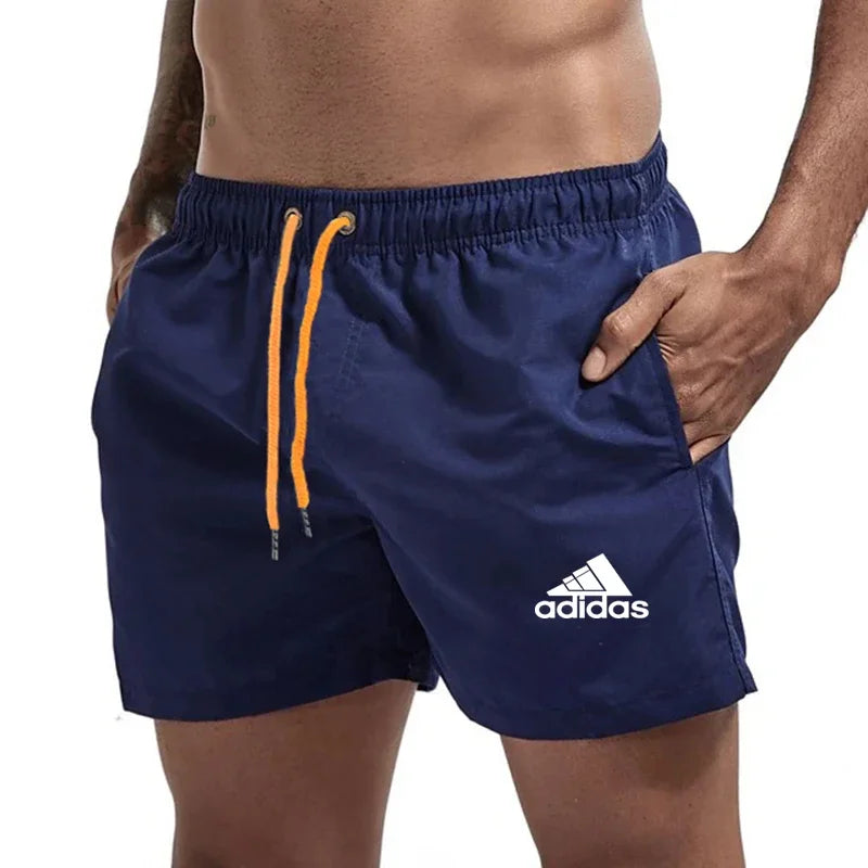 Navy blue Adidas shorts with orange drawstring on a white background