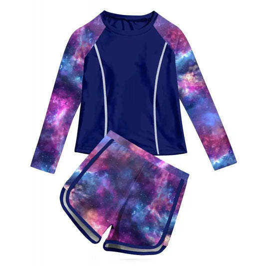Two-piece swimsuit with long-sleeve top and shorts featuring a galaxy print on a white background.