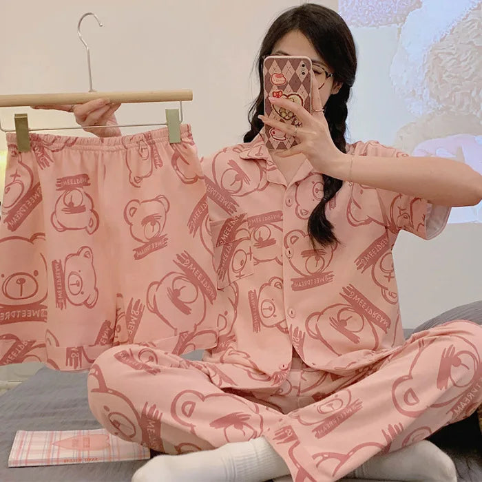 Person wearing pink pajama set with teddy bear design, sitting on a bed.