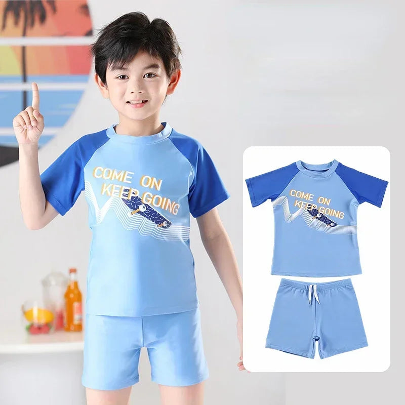 Child wearing a blue and navy swimsuit with 'Come on, keep going' text, pointing upwards.