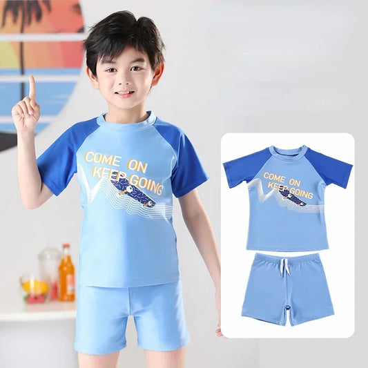 Child wearing a blue and navy swimsuit with 'Come on, keep going' text, pointing upwards.