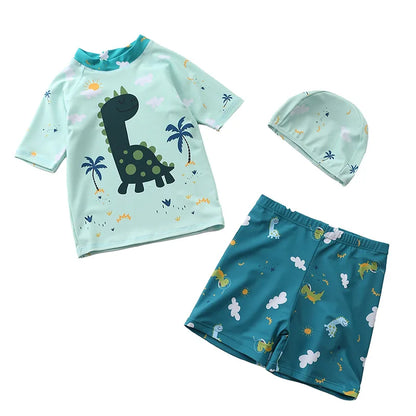 Children's swim set with shirt, shorts, and hat featuring dinosaur and palm tree patterns on a white background.