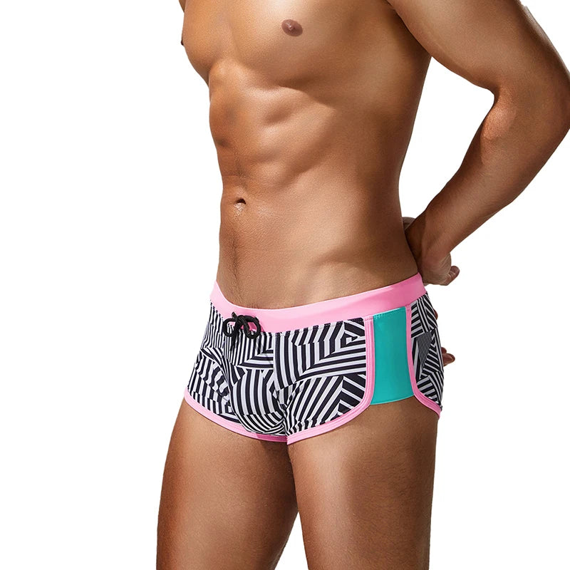 Person wearing black and white patterned swim shorts with pink trim on a white background