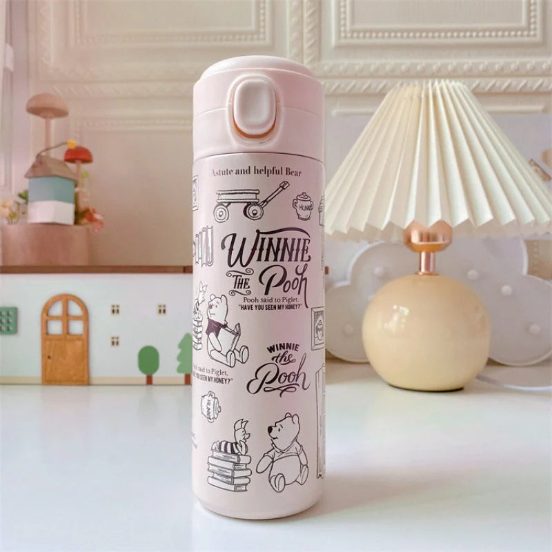 Pink thermos bottle with 'Winnie the Pooh' design on a decorative table