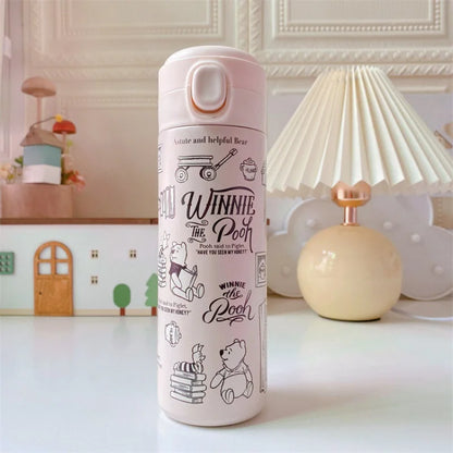 Pink thermos bottle with 'Winnie the Pooh' design on a decorative table