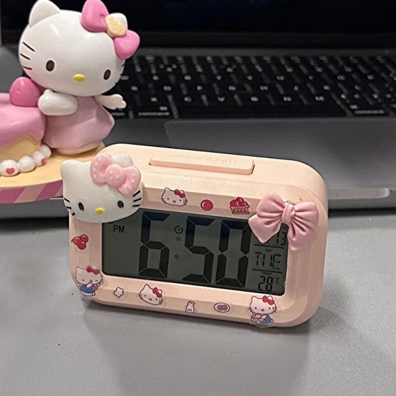 Hello Kitty-themed digital clock on a desk with a laptop in the background