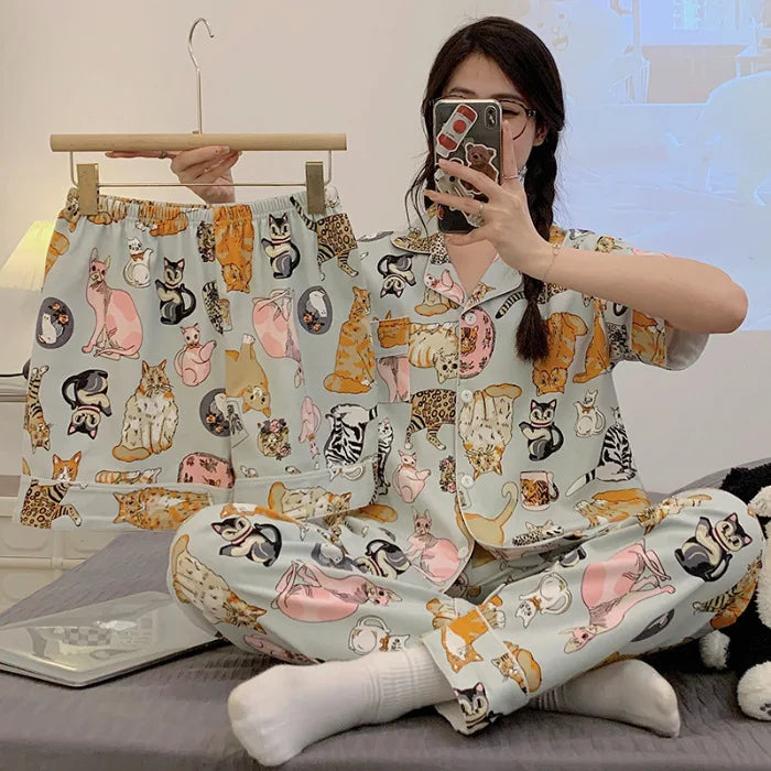 Person wearing a pajama set with cat pattern sitting on a bed.