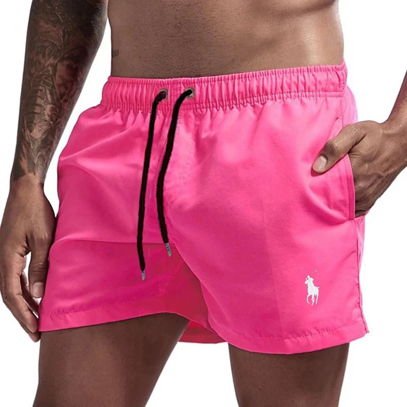 Person wearing bright pink swim shorts with a brand logo on a white background