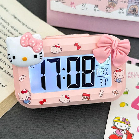 Hello Kitty-themed digital clock on a surface with a calendar in the background