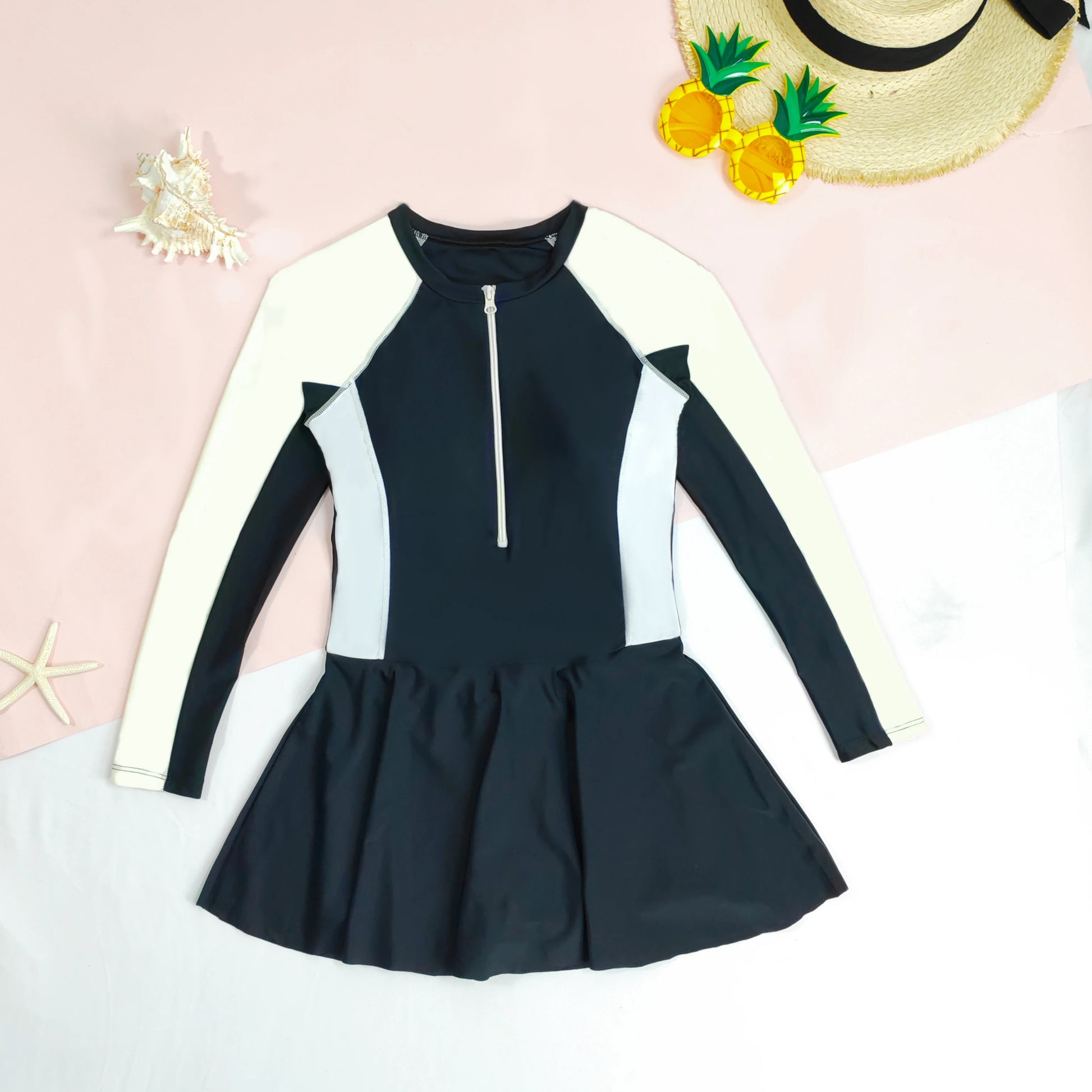Black and white swimsuit with a skirt on a light pink background