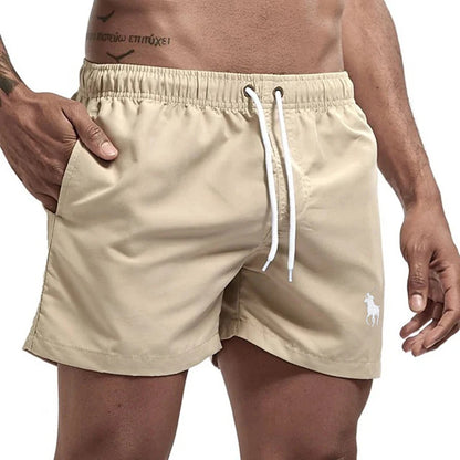 Beige shorts with a white drawstring and logo on a plain background