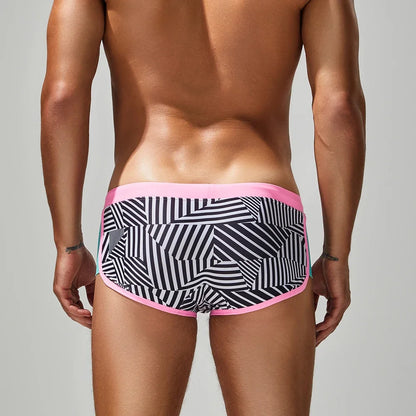 Person wearing black and white patterned underwear with pink waistband on a gray background