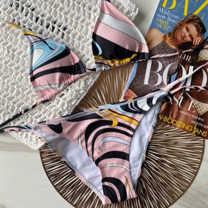 Colorful patterned bikini set on a textured surface with a magazine underneath.