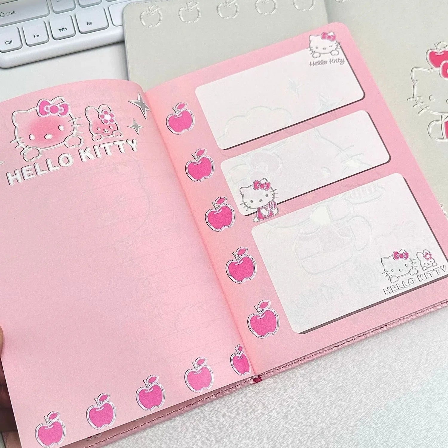 Pink notebook with Hello Kitty design on a white surface