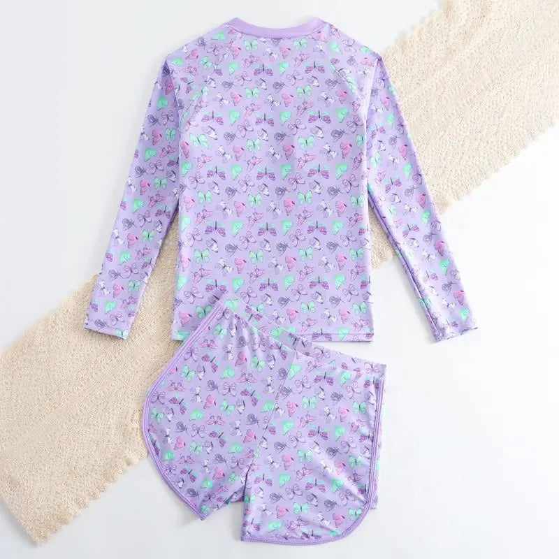 Purple children's swimsuit set with fruit pattern on a textured surface