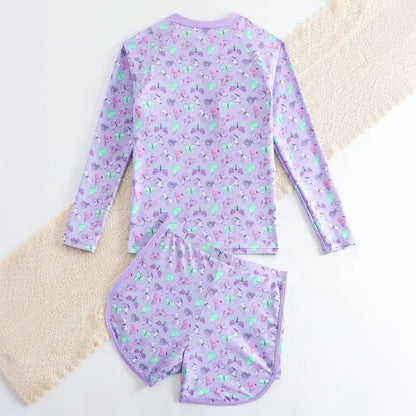Purple children's swimsuit set with fruit pattern on a textured surface