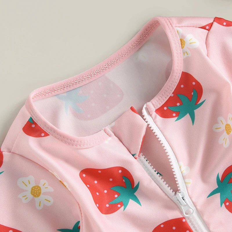 Pink baby outfit with strawberry pattern on a light gray background