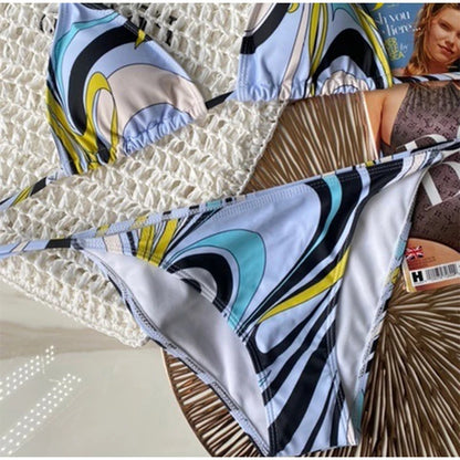 Colorful patterned bikini set on a textured surface with a magazine underneath.