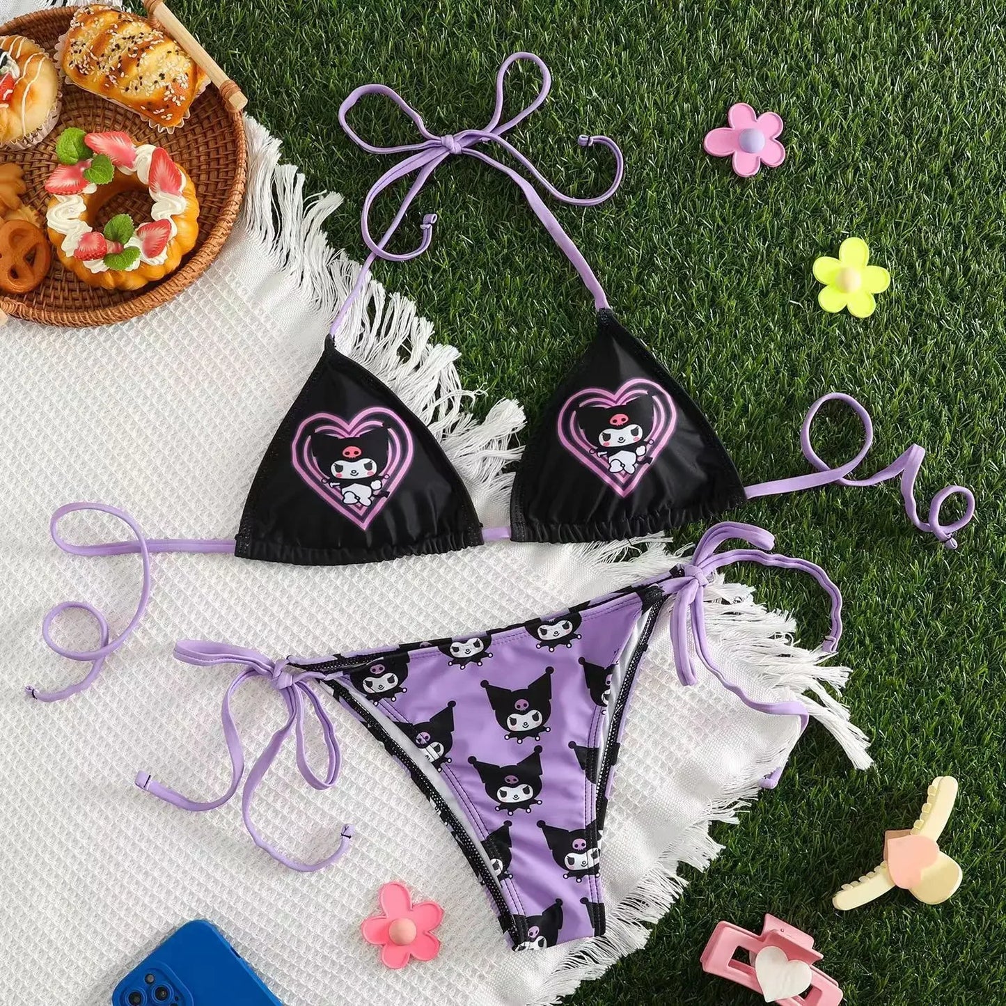 Black bikini with purple accents on a white towel with food and toys around