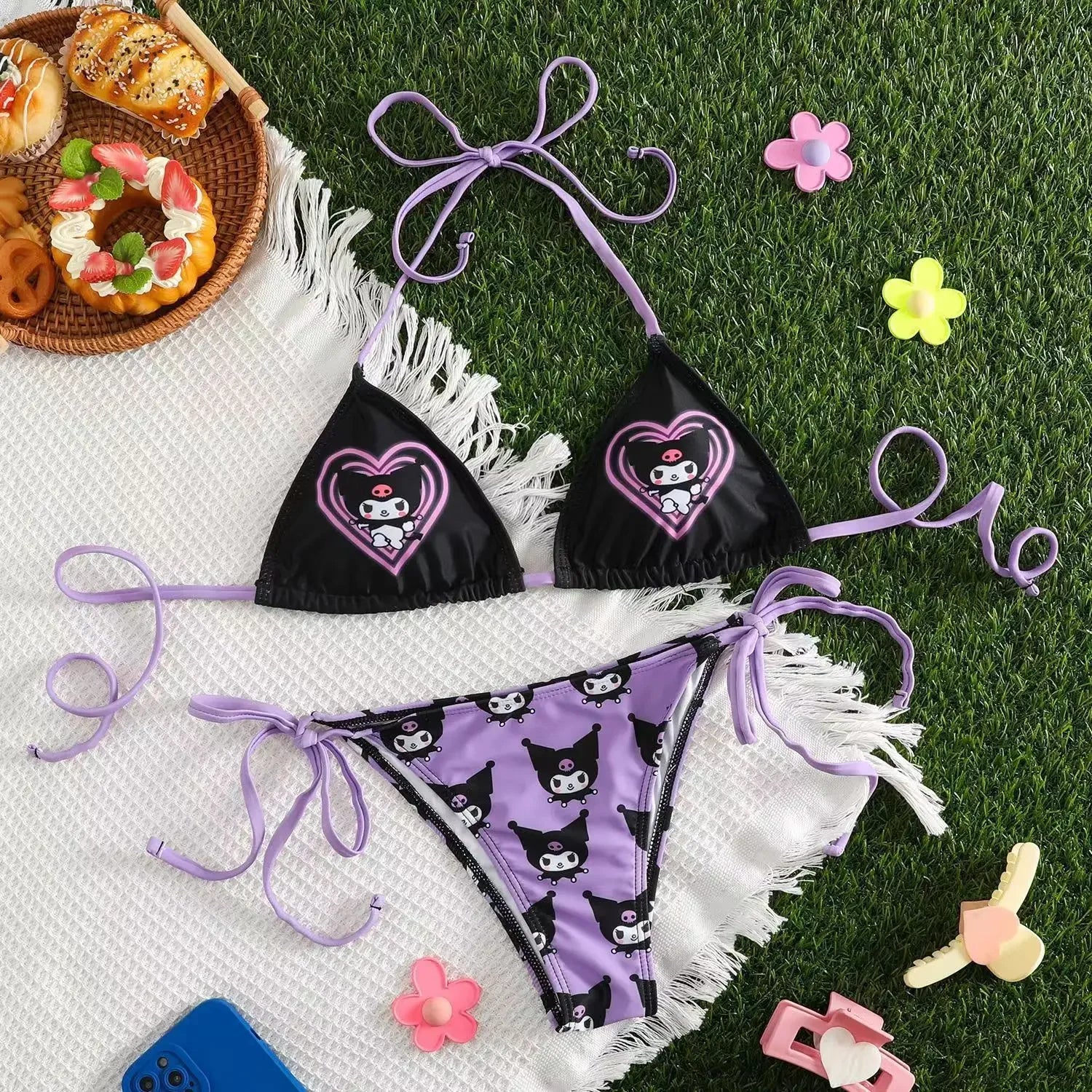 Black bikini with purple accents on a white towel with food and toys around