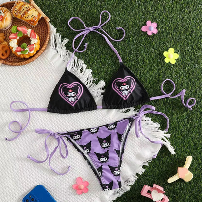 Black bikini with purple accents on a white towel with food and toys around
