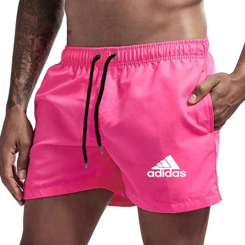 Pink Adidas shorts with orange drawstring on a white background
